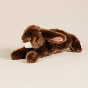 A brown plush rabbit with floral-patterned ears lies on a light background.