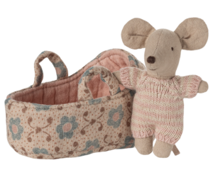 A soft toy mouse in a knitted outfit stands beside a patterned fabric basket.