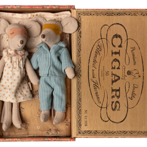 Two plush mice in pajamas and a nightgown rest in a vintage cigar box, surrounded by soft bedding.