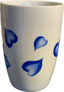 Ceramic cup decorated with blue hearts on a white background.