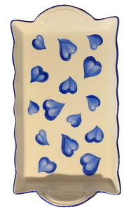 White tray decorated with blue heart shapes, featuring a wavy edge and a handle.
