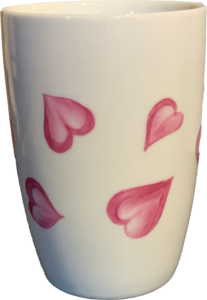 White cup decorated with pink heart designs, showcasing a playful and romantic theme.