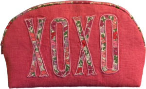 Pink pouch with floral "XOXO" embroidery on the front and a rounded top zipper.