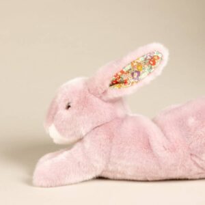 A soft pink stuffed rabbit with floral-patterned ears, lying on its side.