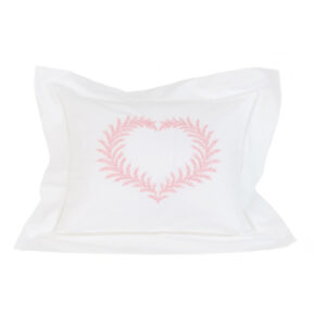 White pillow with pink fern-patterned heart design in the center.