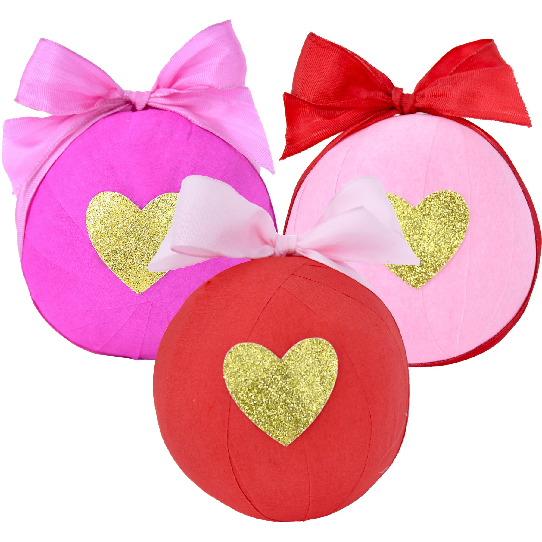 Three decorative surprise balls in pink, red, and light pink, each with a golden heart and ribbon bow.