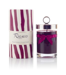 Scented candle in a glass jar beside a decorative box with a striped design.