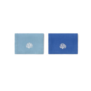 Two cocktail napkins in blue and turquoise linen, each featuring a white coral design.
