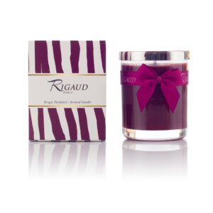 Scented candle in a glass jar beside its decorative box, both featuring purple and white stripes.