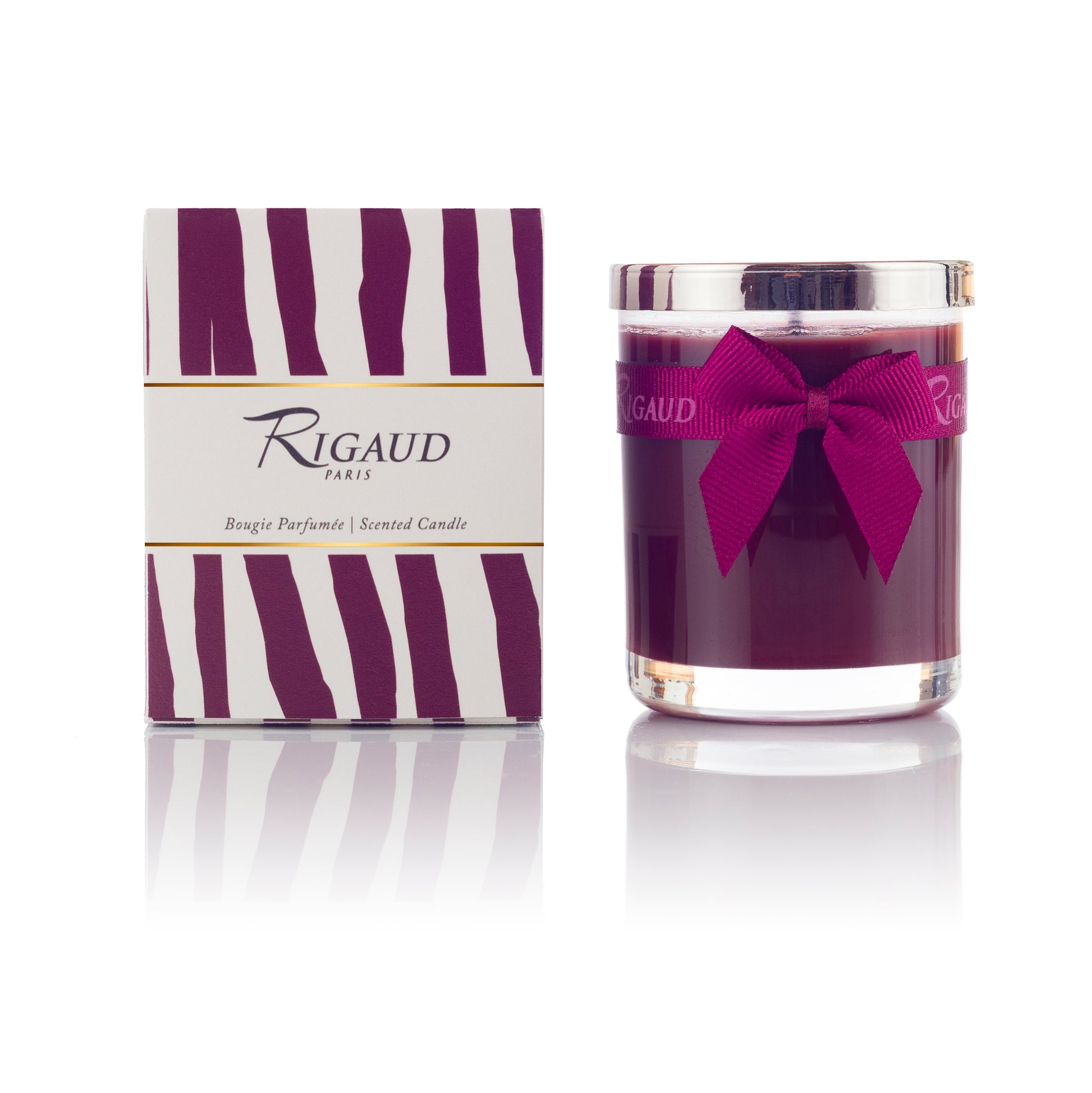 Scented candle in a glass jar beside its decorative box, both featuring purple and white stripes.