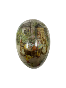 Decorative egg featuring rabbits and ducklings around a basket of colorful eggs near a cottage.