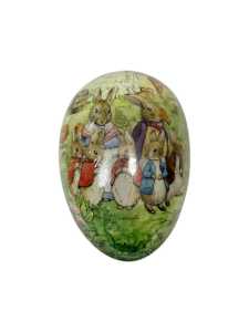Decorative egg features illustrated rabbits in clothing, standing in a grassy scene.