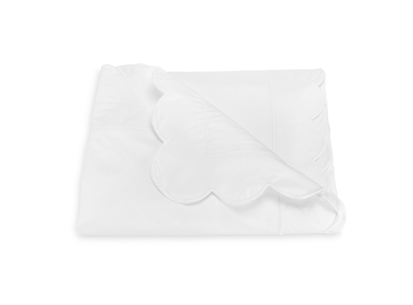 White duvet with a scalloped edge, neatly folded on a flat surface.