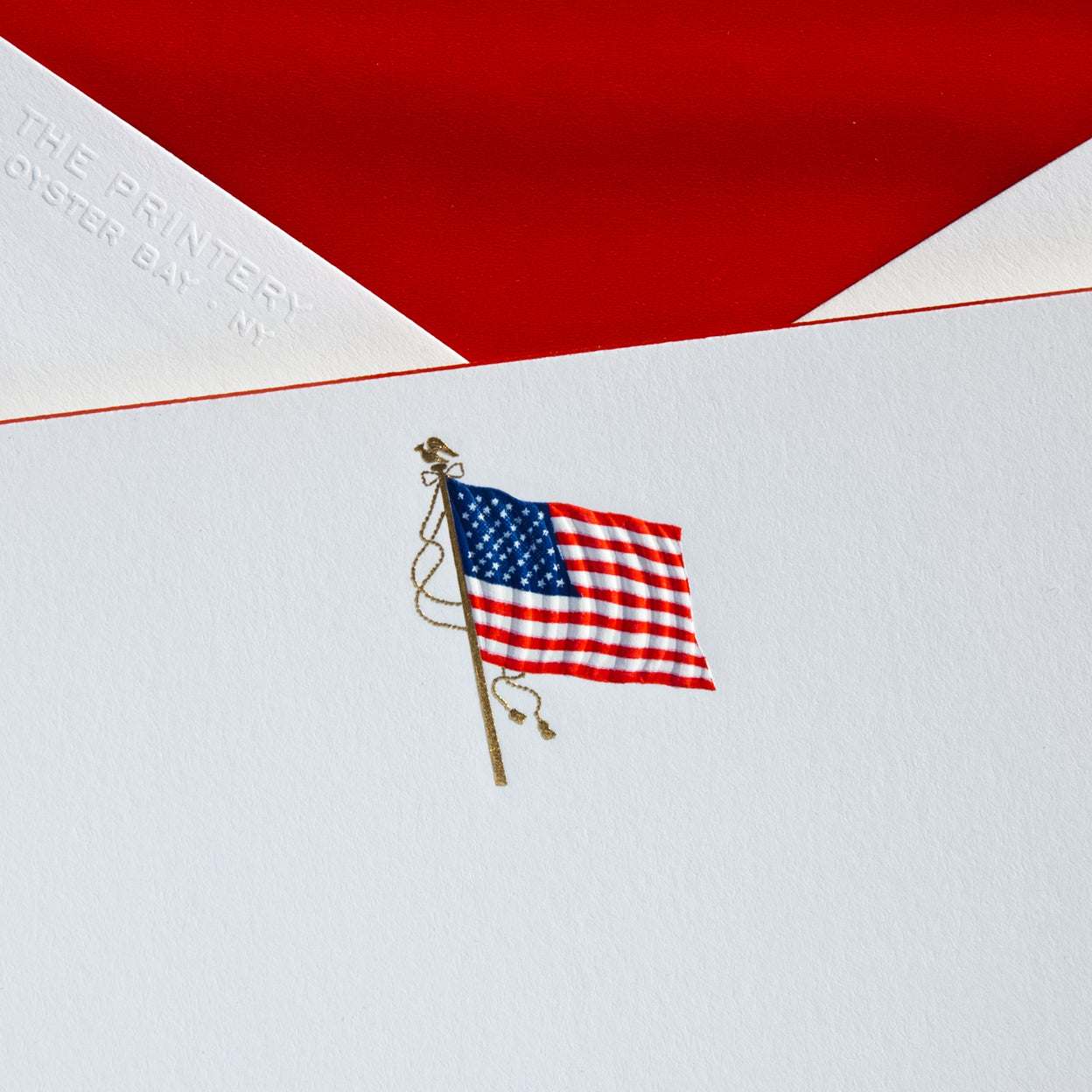 A note card features an illustration of an American flag on a white background, with a red envelope.