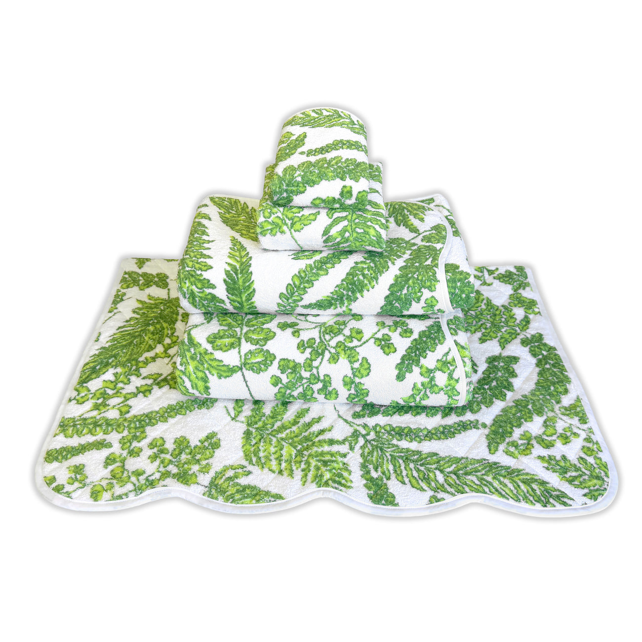 Stack of green and white towels with fern patterns, arranged on a decorative mat.