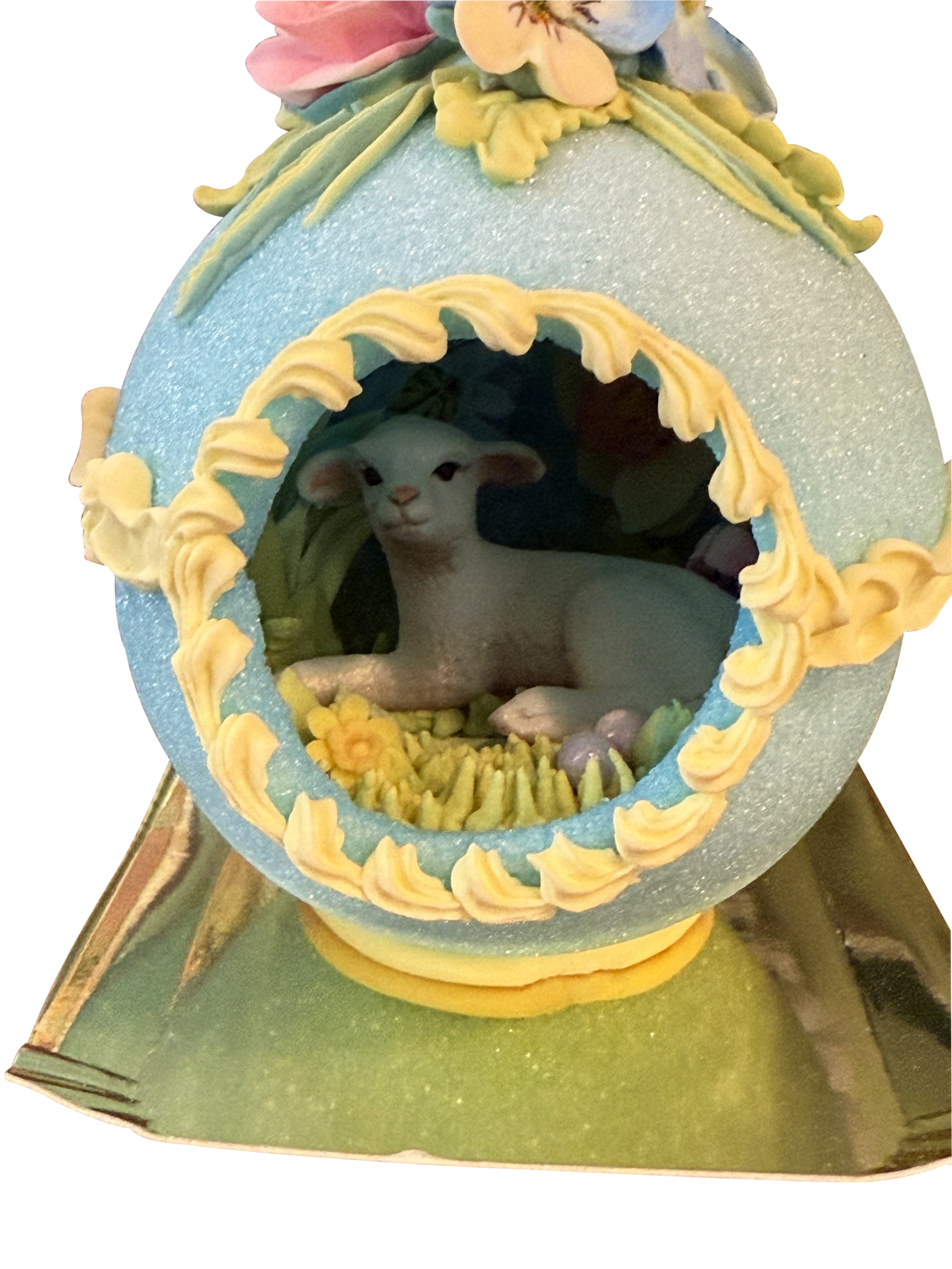 Sugar Egg Medium Lamb Horizontal A decorative sugar egg featuring a lamb surrounded by flowers and grass inside.