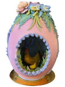 Decorative pink egg with flowers, featuring a hen and chick inside a floral scene.