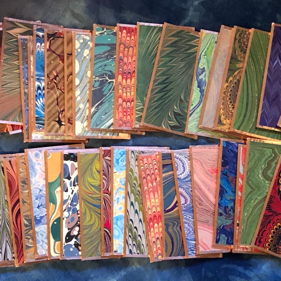 A collection of colorful marbled paper sheets arranged in overlapping stacks.