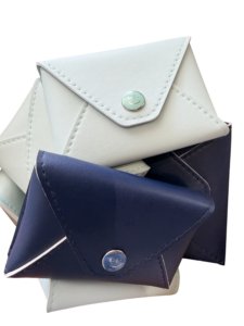 Three triangular leather wallets in light green and navy stacked together, featuring snap closures.