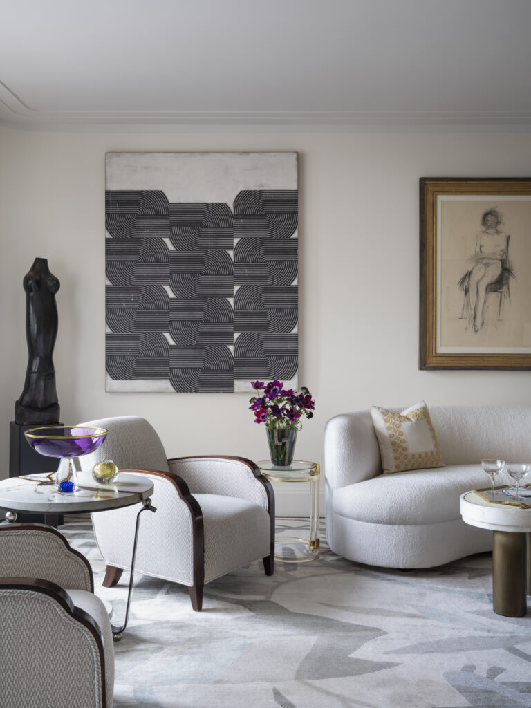 A stylish living room features modern furniture, abstract art, and a vase of flowers on a table.