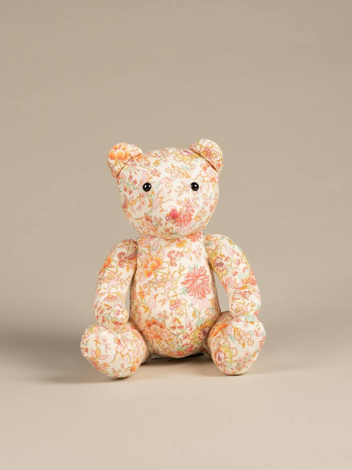 A floral-patterned teddy bear sits upright against a neutral background.