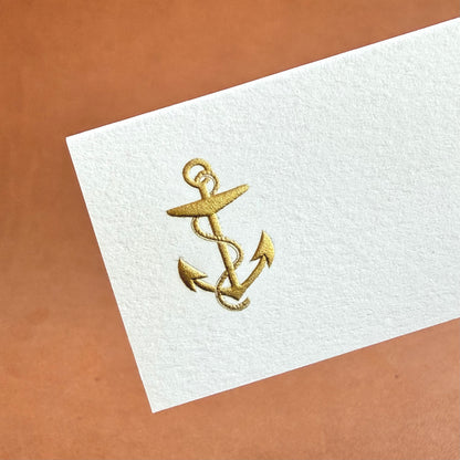 A white card features a gold anchor design with intertwined ropes and two curved anchors.