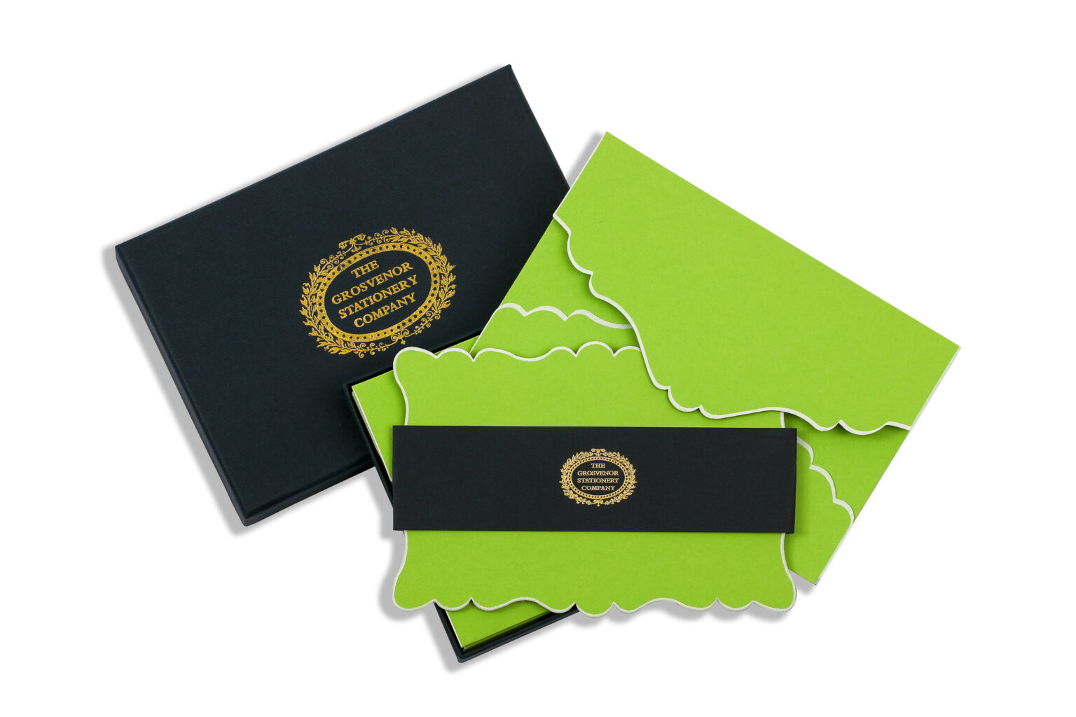 A black box contains green stationery with decorative edges and a black band featuring a gold logo.