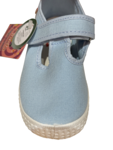 Light blue T-strap sneaker with a white sole and adjustable strap. Tag attached.