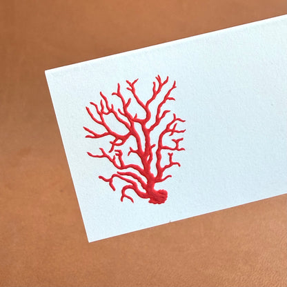 A white place card features a detailed red coral illustration.
