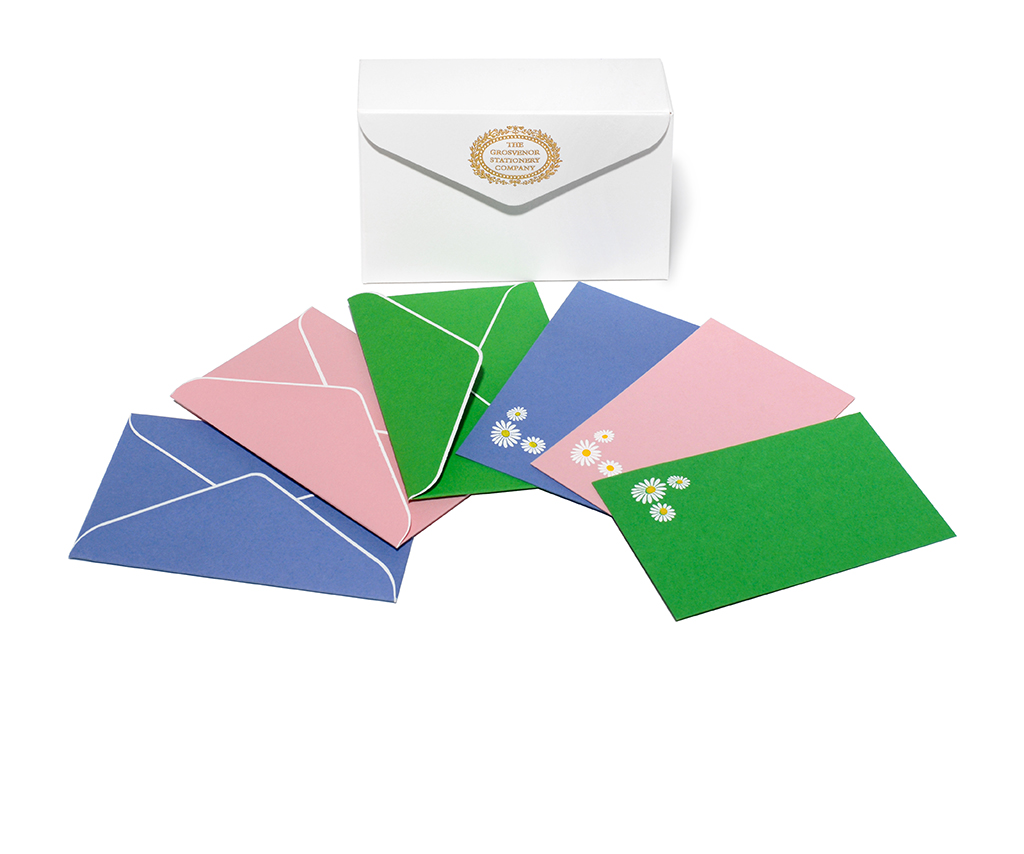 A white box with a decorative label holds colorful envelopes in pink, blue, green, and decorated with daisies.