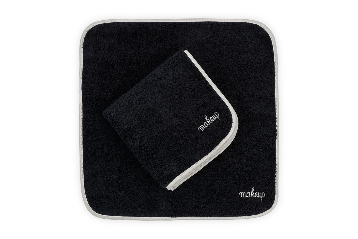Two black makeup towels with white trim, one larger and one folded, displaying the word "makeup.