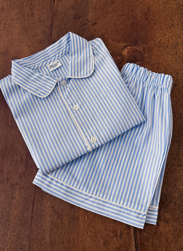 Blue and white striped pajama set, featuring a collared shirt and matching shorts, neatly folded on a wooden surface.