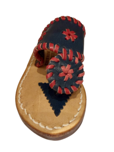 A blue leather sandal with red stitching and floral designs on the upper.