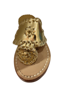 Gold sandals with floral design and braided details on a light-colored sole.