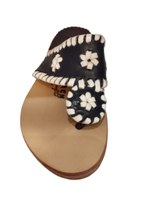 Navy sandal with white floral design and braided strap, viewed from above.