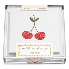 A clear box contains notecards featuring two cherries and the phrase "with a cherry on top.